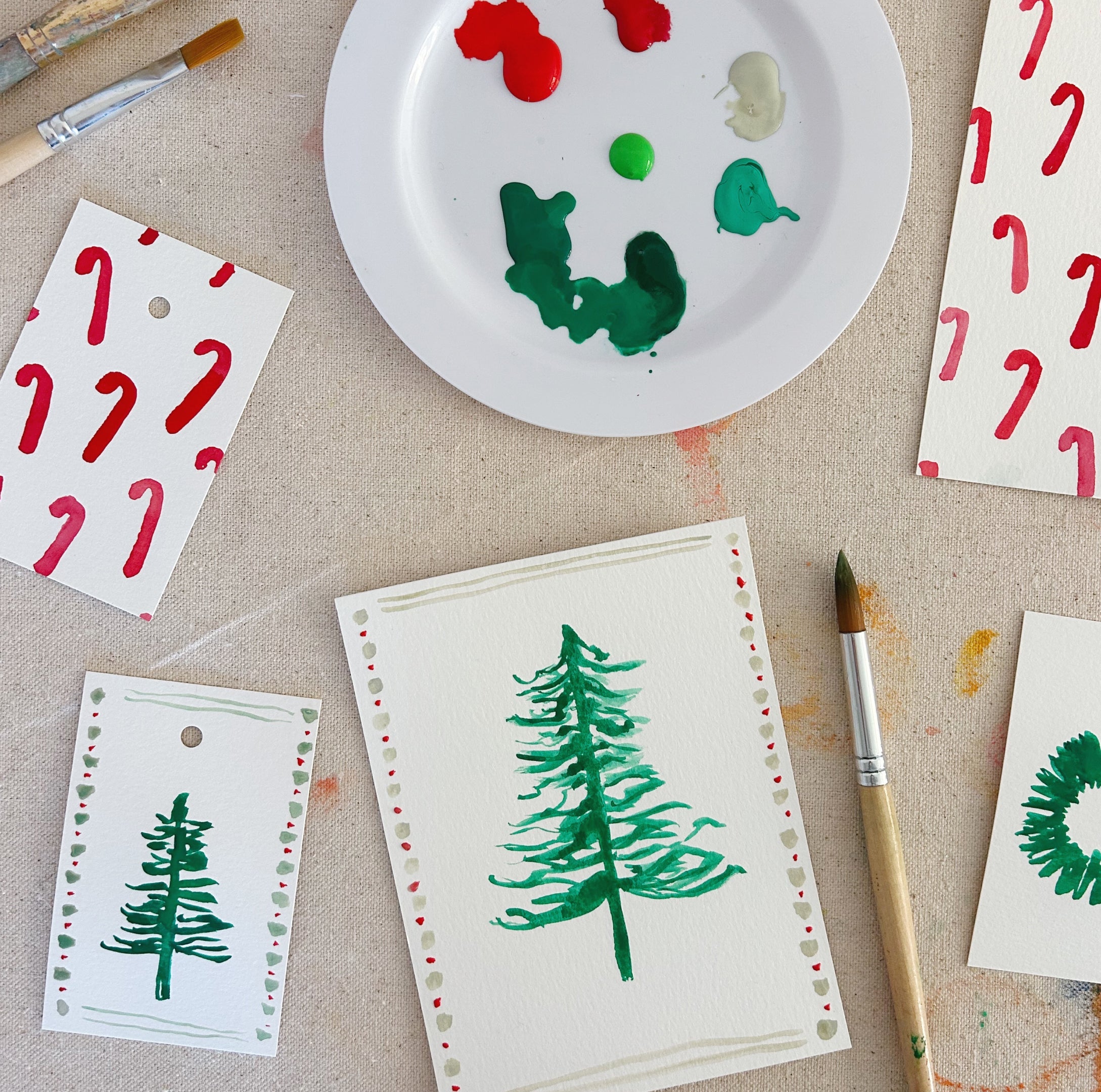 Watercolor paint palette and watercolor painting of Christmas tree and candy canes